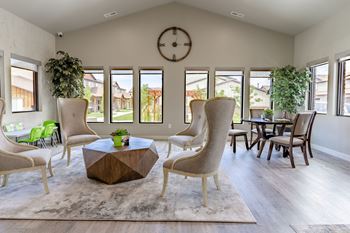 A living room with a table and chairs and a clock on the wall