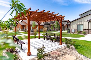 A wooden pergola with a bench in a courtyard