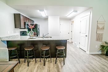 A kitchen with bar stools and a counter top in a living room