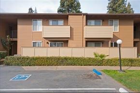 Sacramento apartment for rent - A parking space with a blue sign is in front of a tan apartment building.