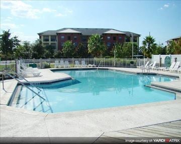 Orlando apartment for rent - A swimming pool with a metal railing and chairs around it.