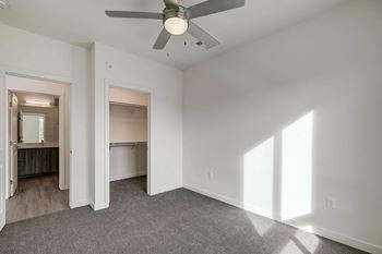 A bedroom with white walls and a ceiling fan