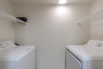 Two white front load washing machines in a small laundry room