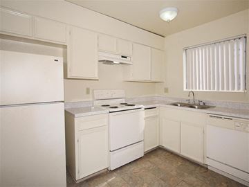 El Cajon apartment for rent - A white kitchen with a refrigerator, stove, and sink.