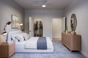 Las Vegas apartment for rent - A bedroom with a large bed and a clothing rack in the background.