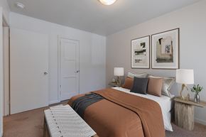 Seattle apartment for rent - A bedroom with a bed, two lamps, and two framed pictures on the wall at Lake Washington Apartments, 98118