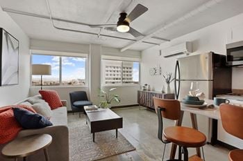 A modern living room with a grey couch, a red throw pillow, and a wooden coffee table.
