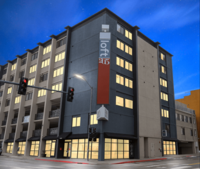 Reno apartment for rent - A modern building with a dark grey facade and a red sign on the front at LOFT 205 Apartments, Reno, NV