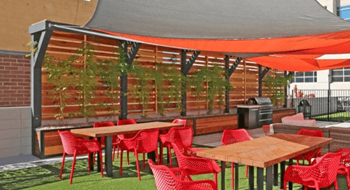 A patio with red chairs and tables under a grey canopy.