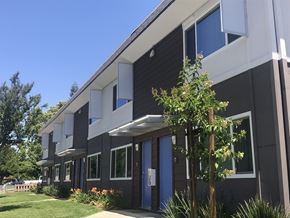Vacaville apartment for rent - a picture of a building with black and white siding and a blue door at MEADOWS HOLLY, VACAVILLE California