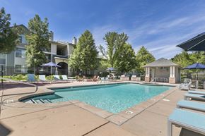 Cottonwood Heights apartment for rent - a swimming pool with chairs and umbrellas and a building in the background at Ascent Apartments, Cottonwood Heights, UT