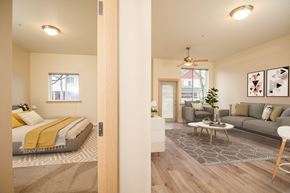 Fairview apartment for rent - A bedroom with a bed, a couch, a coffee table, and a ceiling fan. at Fairview Village Apartments, Fairview, OR