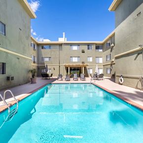 Sherman Oaks apartment for rent - A large swimming pool in the middle of a courtyard surrounded by chairs and buildings.