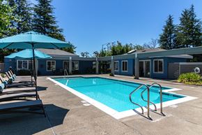San Leandro apartment for rent - San Leandro, CA Apartments - Gateway Apartments - Pool with Blue Umbrellas, Lounge Chairs, and Lush Landscaping