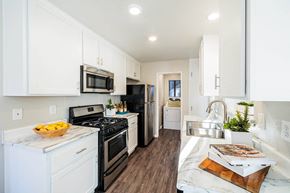 Lake Forest apartment for rent - a kitchen with white cabinets and black appliances at SERRANO HIGHLANDS APARTMENT HOMES, California