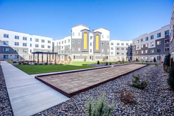 Reno apartment for rent - A modern building with a yellow door and a gravel pathway in front.