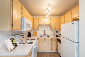 Vancouver apartment for rent - A kitchen with a white refrigerator and wooden cabinets.at Vancouver Mall Apartments, Vancouver, 98662