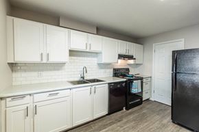Orem apartment for rent - a kitchen with white cabinets and black appliances at Mountain Run Apartments, Orem, Utah