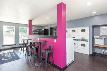 A kitchen with a pink pillar and a bar with stools