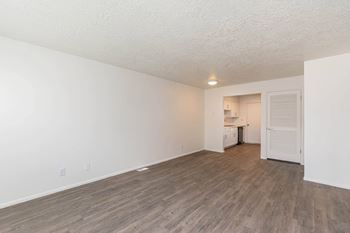A living room and kitchen with wood flooring and white walls