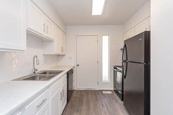 A kitchen with white cabinets and a black refrigerator