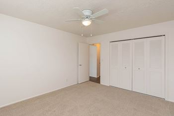 A bedroom with a ceiling fan and a closet
