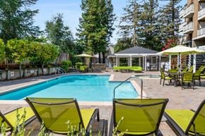 Castro Valley apartment for rent - A pool surrounded by green chairs and trees.