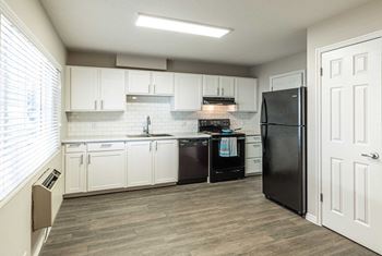 A kitchen with white cabinets and a black refrigerator