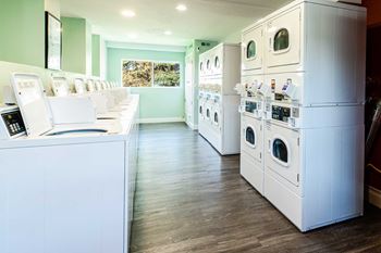 A laundry room filled with white appliances and washers and dryers