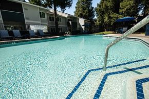 Sacramento apartment for rent - a large swimming pool with chairs and a resort style building