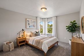 Canby apartment for rent - A bedroom with a large bed and a window overlooking a green landscape.