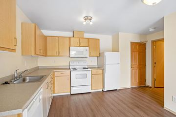 Burien apartment for rent - A kitchen with wooden cabinets and white appliances.