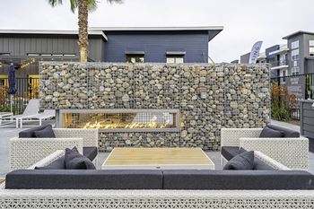 A stone wall with a fireplace and a wooden coffee table in front of it