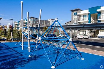 A playground in a parking lot in front of an apartment complex