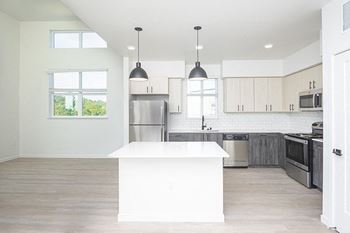 A kitchen with white cabinets and a white island