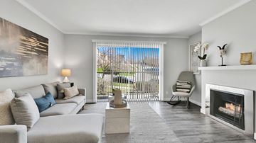 Salt Lake City apartment for rent - A modern living room with a grey sofa, a grey armchair, a grey coffee table, a fireplace, and a painting on the wall.