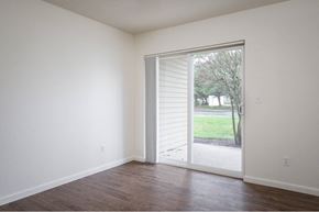 Vancouver townhouse for rent - an empty living room with a sliding glass door to a yard at Quail Run Apartments, Vancouver, Washington