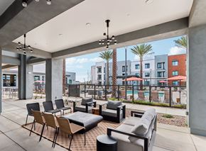 Maricopa apartment for rent - A patio with a black couch and chairs with a pool and buildings in the background at Ironwood Ranch Apartments,Maricopa,AZ,85138
