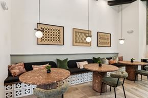 Maricopa apartment for rent - A modern dining area with a black sofa, round tables, and hanging lights at Ironwood Ranch Apartments,Arizona,85138
