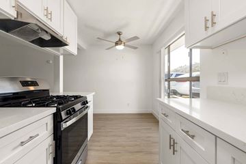 La Mesa apartment for rent - A kitchen with white cabinets and a black stove top.