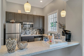 A kitchen with a refrigerator, microwave, and oven.