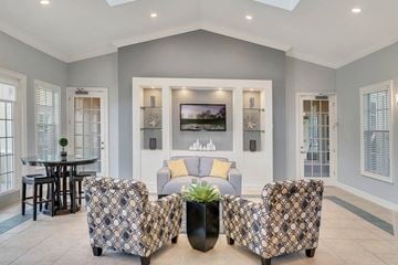 Orlando apartment for rent - A living room with a patterned chair and a television on the wall.
