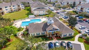 Orlando apartment for rent - A bird's eye view of a residential area with houses, cars, and a swimming pool at The Villages on Millenia Apartments, Orlando, FL