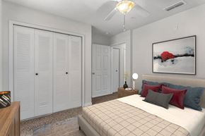 Orlando apartment for rent - A bedroom with a bed, a nightstand, and a painting on the wall at The Villages on Millenia Apartments, Orlando, FL, 32839