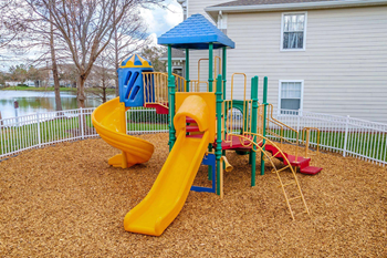A playground with a yellow slide and a blue roofed structure.