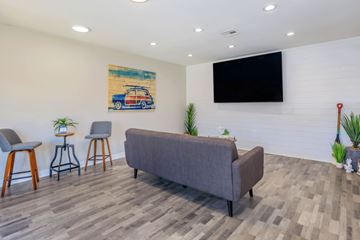 Las Vegas apartment for rent - A living room with a grey couch, two chairs, a bar stool, a plant, and a painting on the wall.