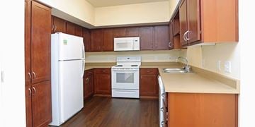 Colorado Springs apartment for rent - A kitchen with a white refrigerator, white stove, and brown cabinets.
