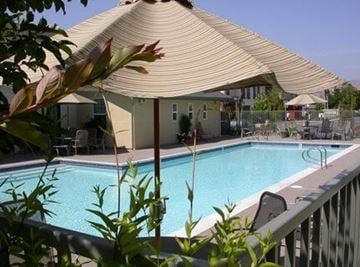 San Jose apartment for rent - A pool under a shade structure with a building in the background.