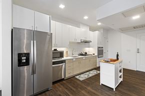 Newton apartment for rent - A modern kitchen with a stainless steel refrigerator and wooden flooring. at Trio Newton Apartments, Newton, Massachusetts