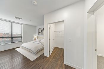 A bedroom with a bed, a window, and a wooden floor.
